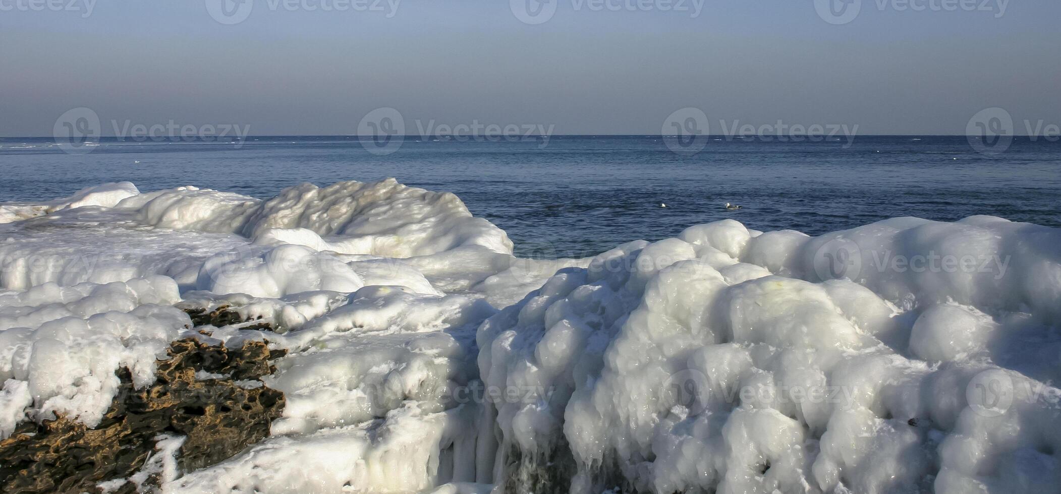 Iced rocks and stones near the shore in the Black Sea at the end of winter photo
