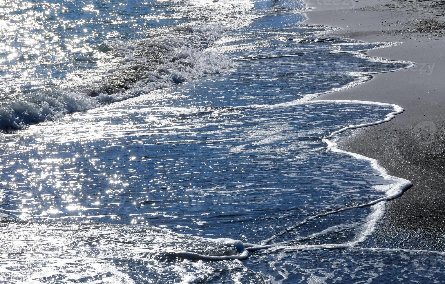 Bright reflections on the water on a sunny day on the sandy shore of the Black Sea photo