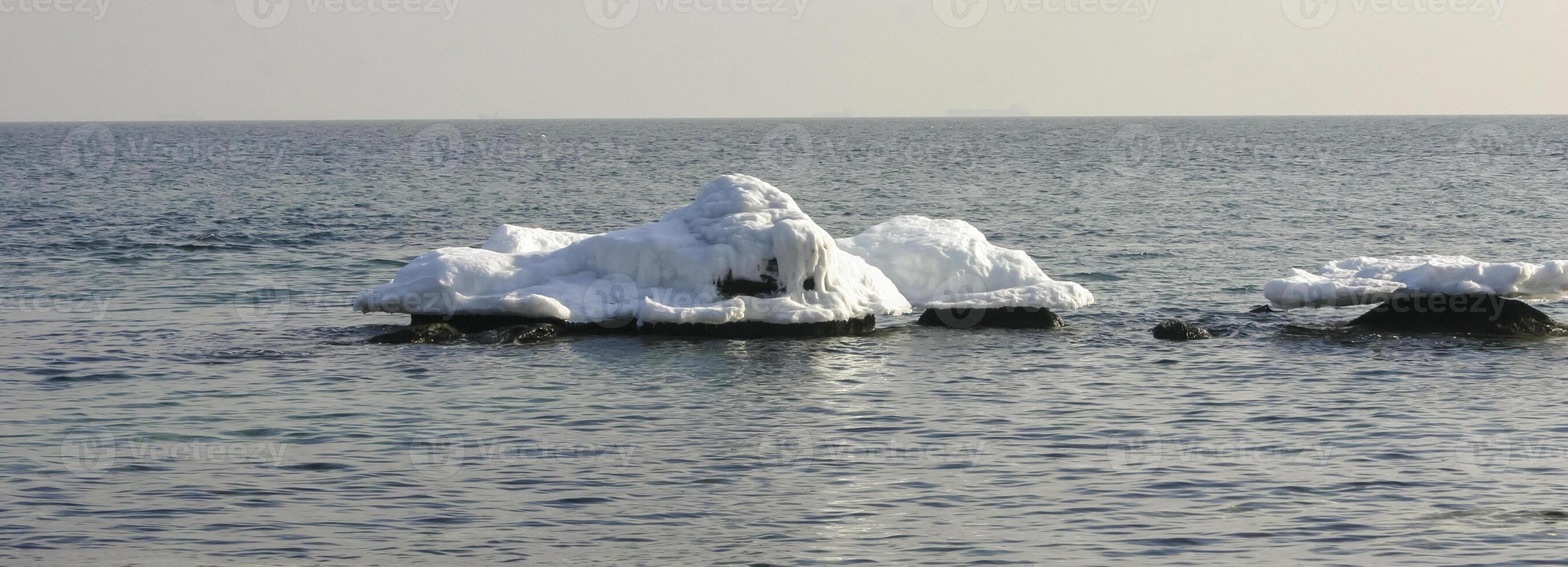 Iced rocks and stones near the shore in the Black Sea at the end of winter photo