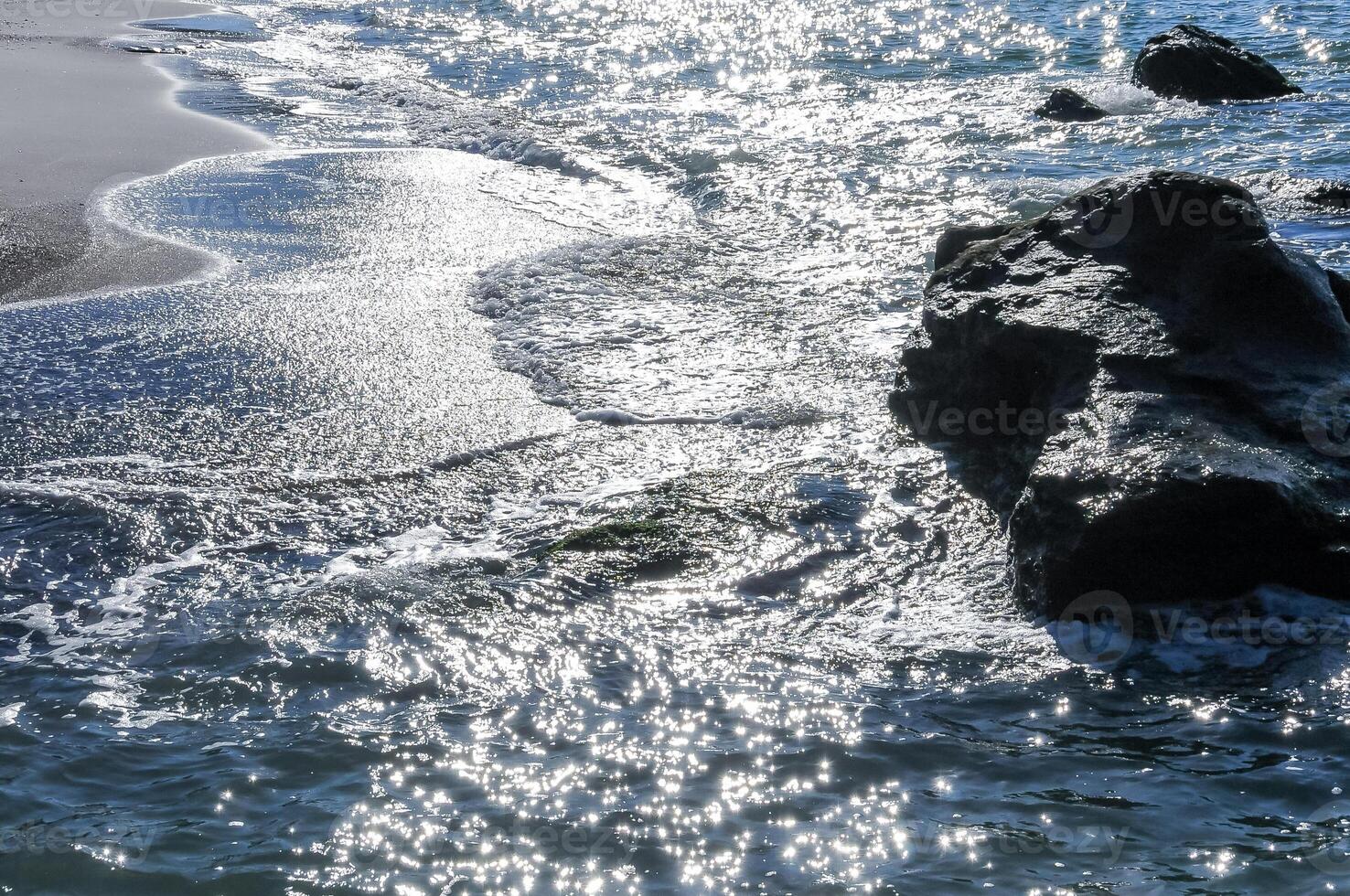 Bright reflections on the water on a sunny day on the sandy shore of the Black Sea photo