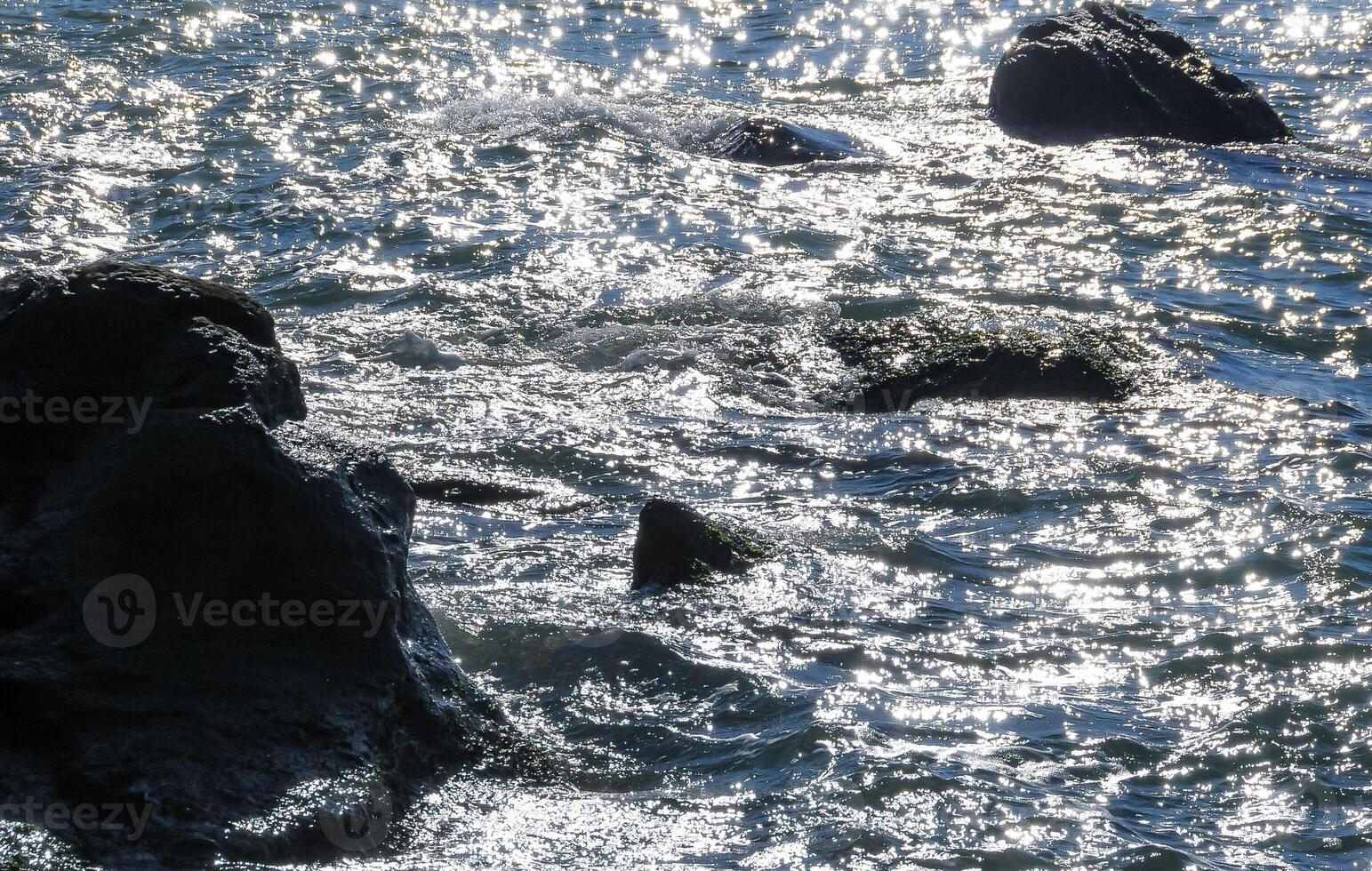 Bright reflections on the water on a sunny day among the coastal rocks near the Black Sea coast photo