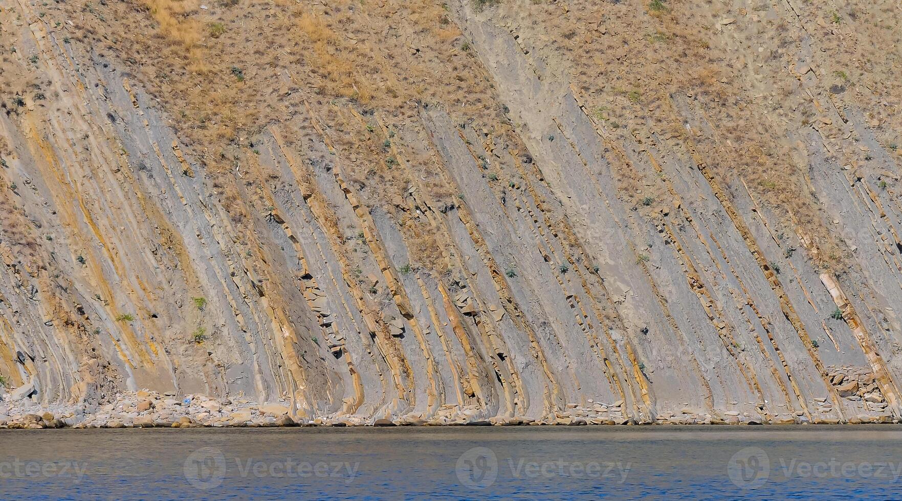 Vertically located layers of sedimentary rocks in coastal rocks in eastern Crimea photo