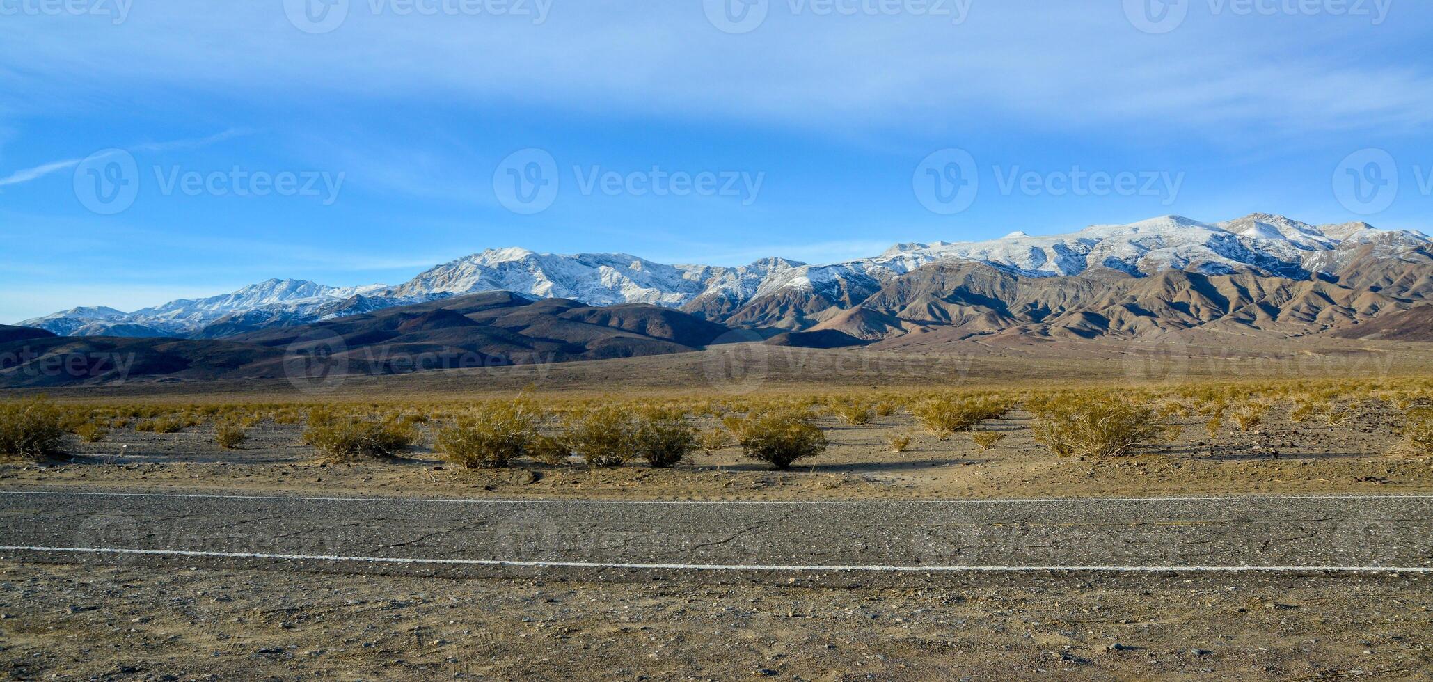 Landscape of wet clay desert in winter against the backdrop of snow-capped mountains in the Death Valley area photo