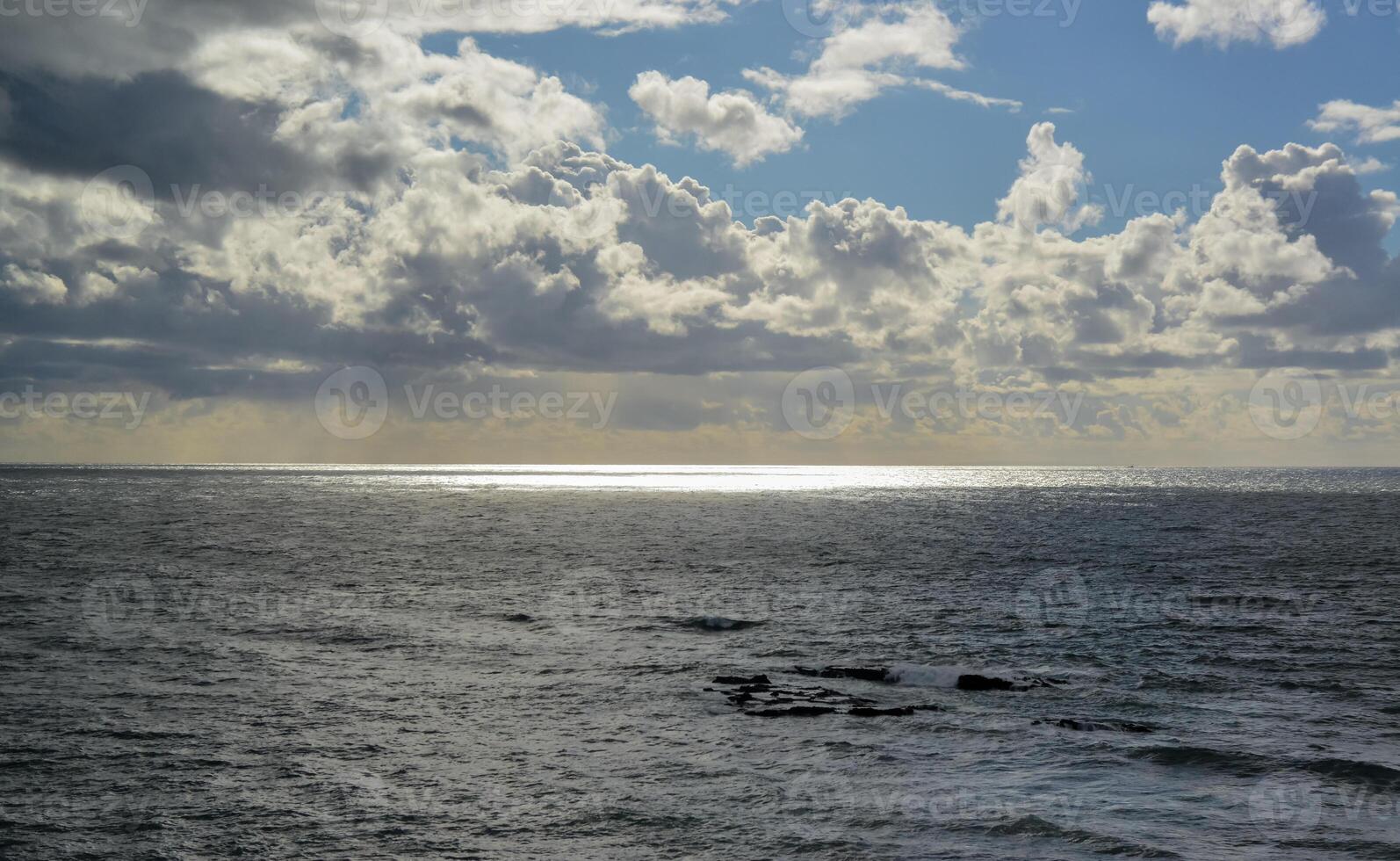 The sun's rays break through thick clouds over the Pacific Ocean, a sunspot is all over the water. photo