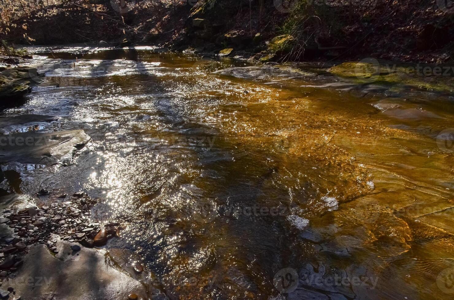 Reflection of the sun in the water, a small river in the autumn in the forest in the parkon Brandywine Creek in Cuyahoga Valley National Park, Ohio. USA photo