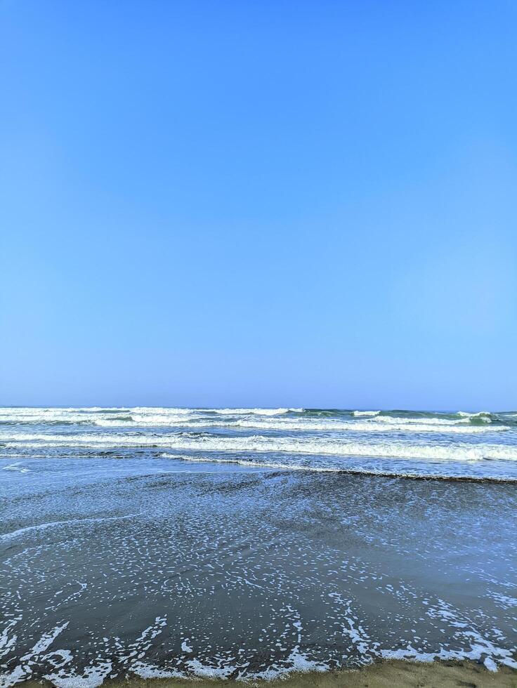 The calm waves crashing towards the beach splashing the sea water photo