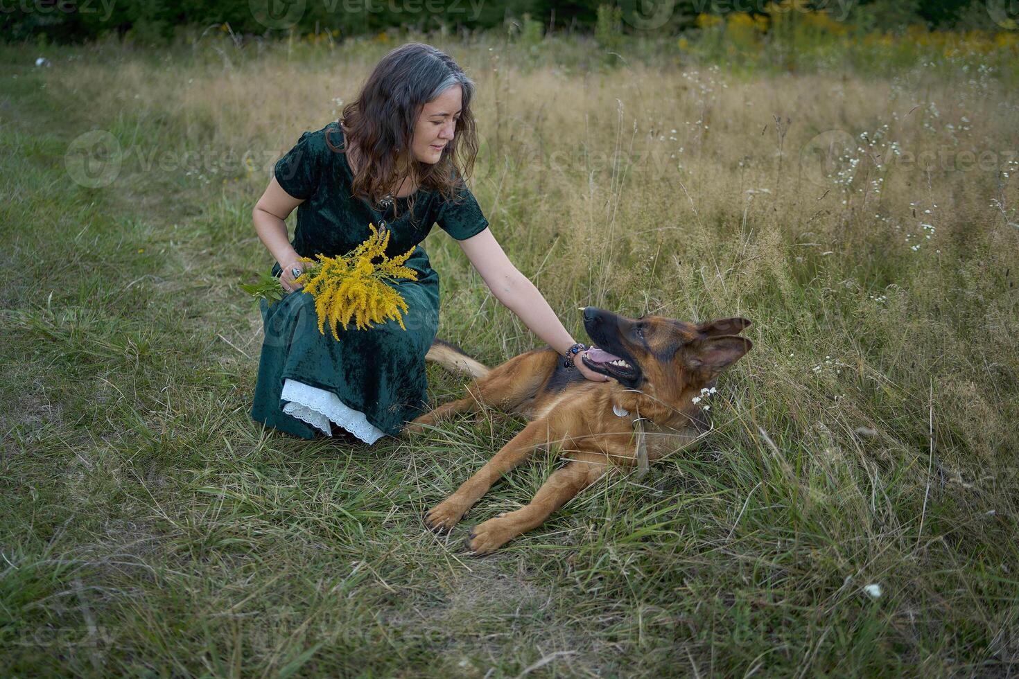 a woman in a Whimsical Aesthetic style dress with a German shepherd in a field photo