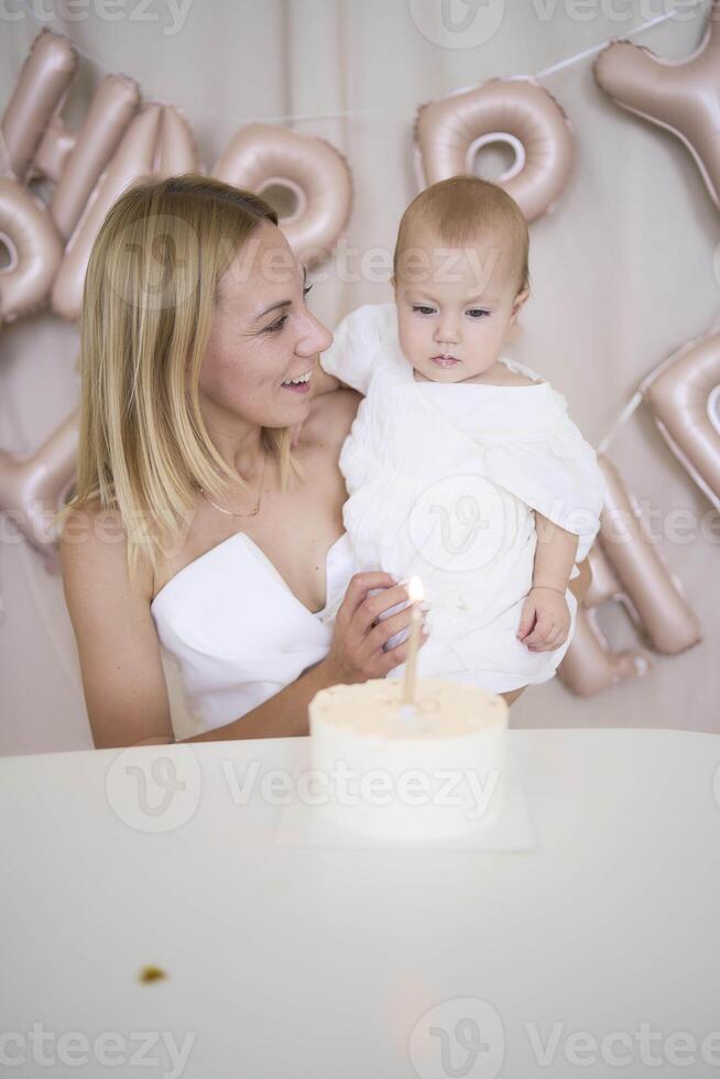 baby girl tries her first birthday cake with mom and pre-teen sister photo