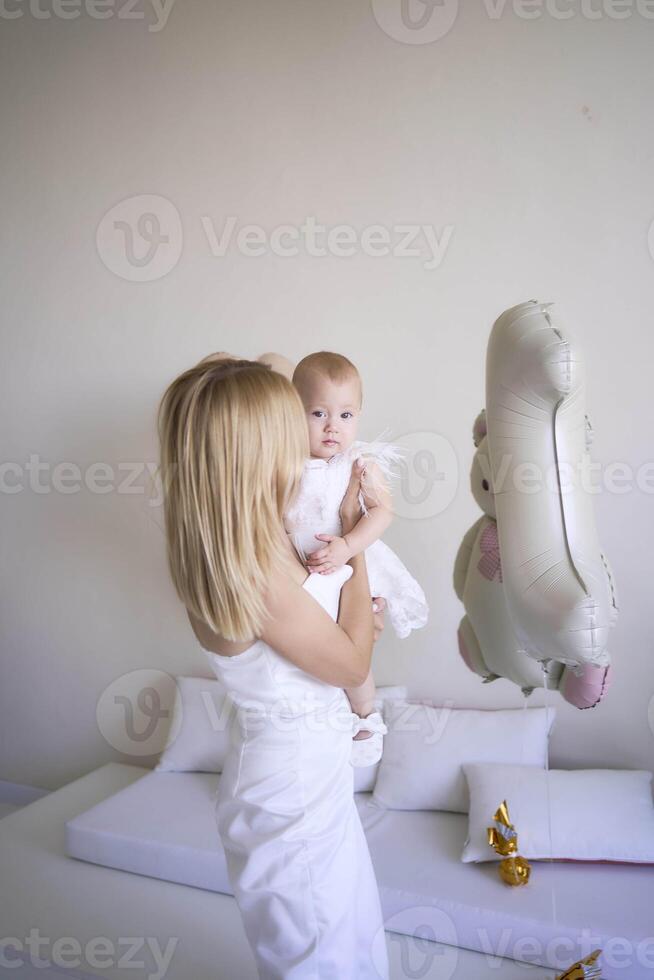 mother with a baby girl in a stylish white minimalist interior in white clothes photo