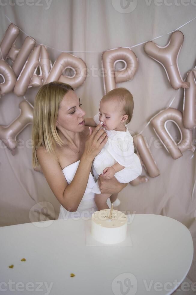 baby girl tries her first birthday cake with mom and pre-teen sister photo