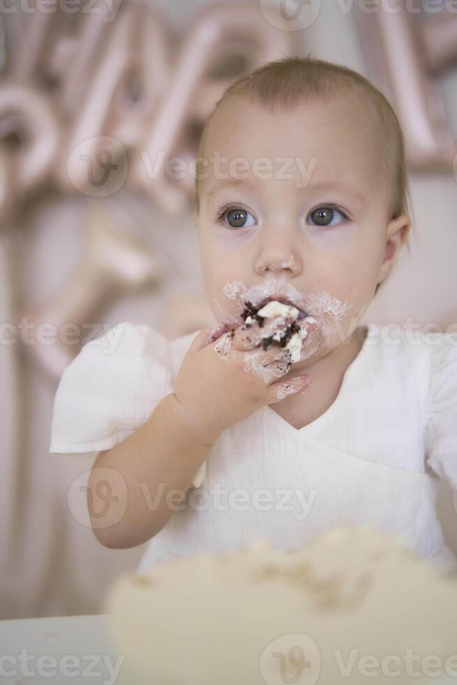 baby girl tries her first birthday cake with mom and pre-teen sister photo