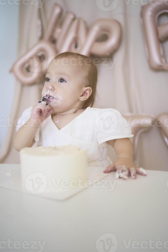 baby girl tries her first birthday cake with mom and pre-teen sister photo