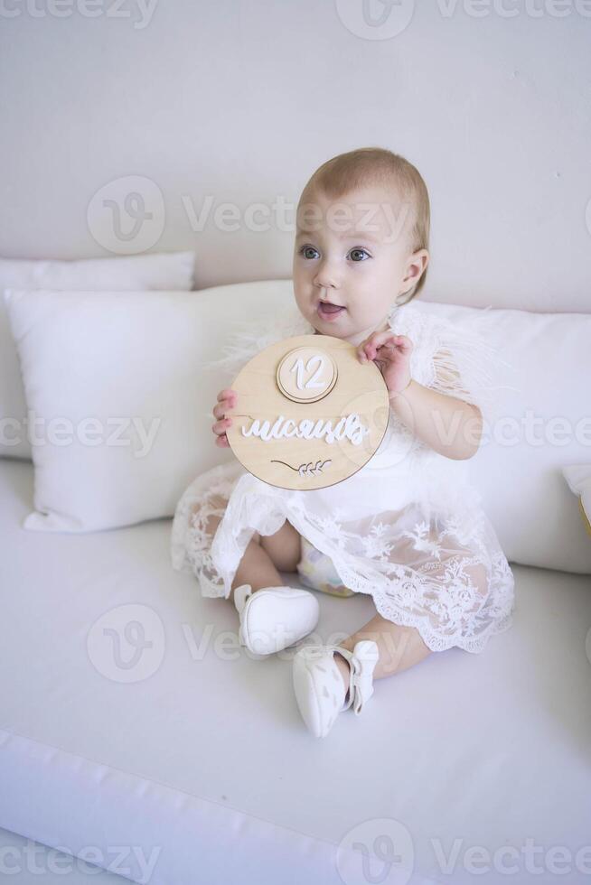 photo session on the first birthday of a baby girl, baby hold decor with writed 12 months in ukrainian language