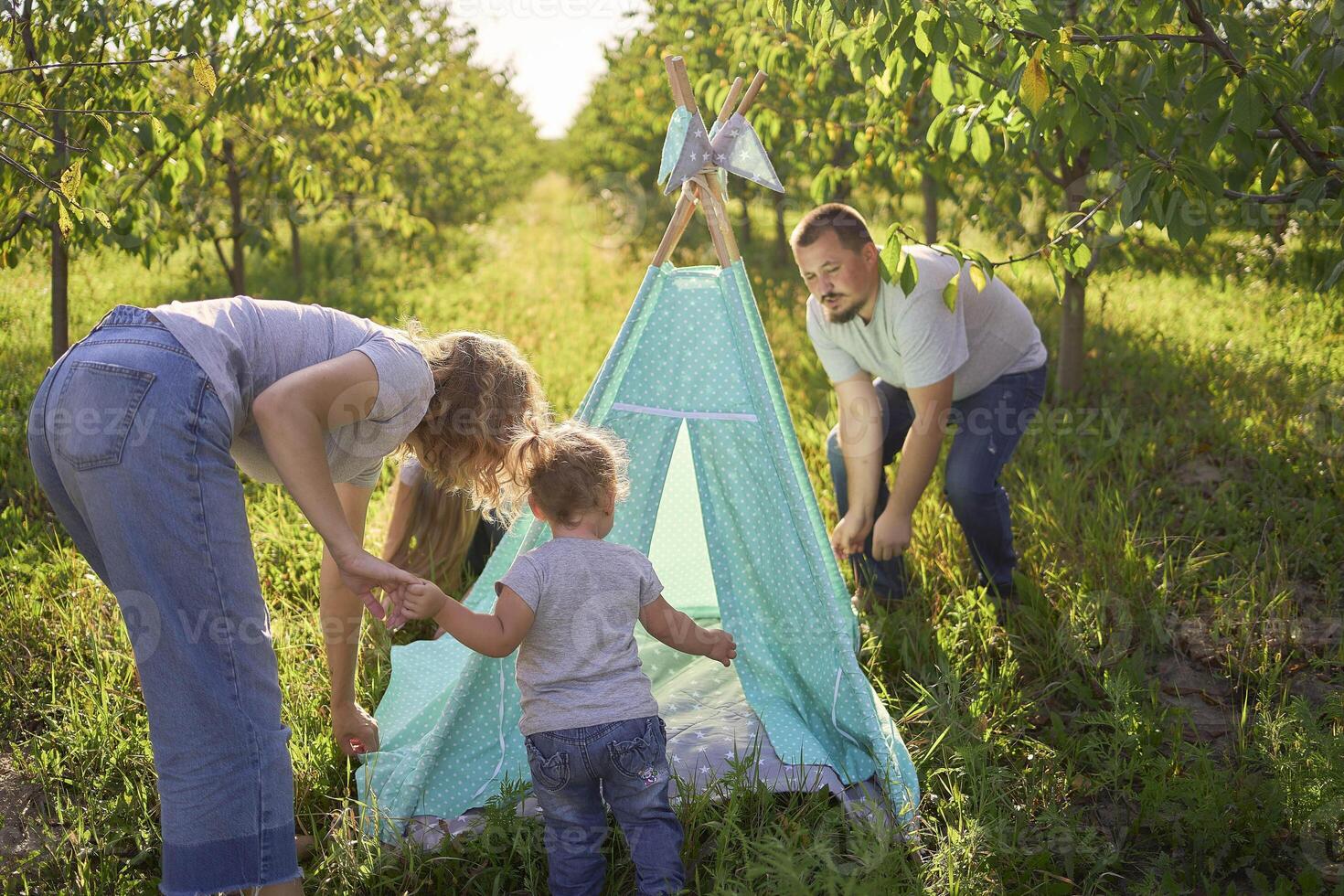 family with toddler playing in wigwam in garden photo