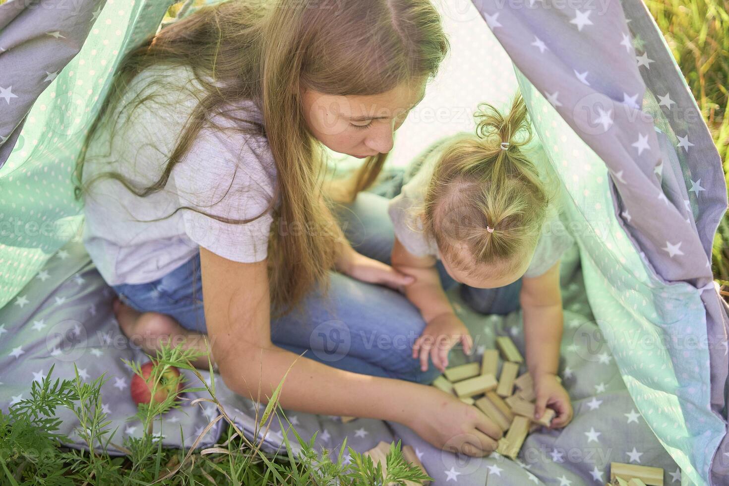 family with toddler playing in wigwam in garden photo