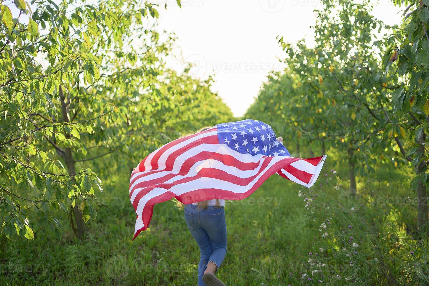 teenage girl running with american flag at independence day picnic photo