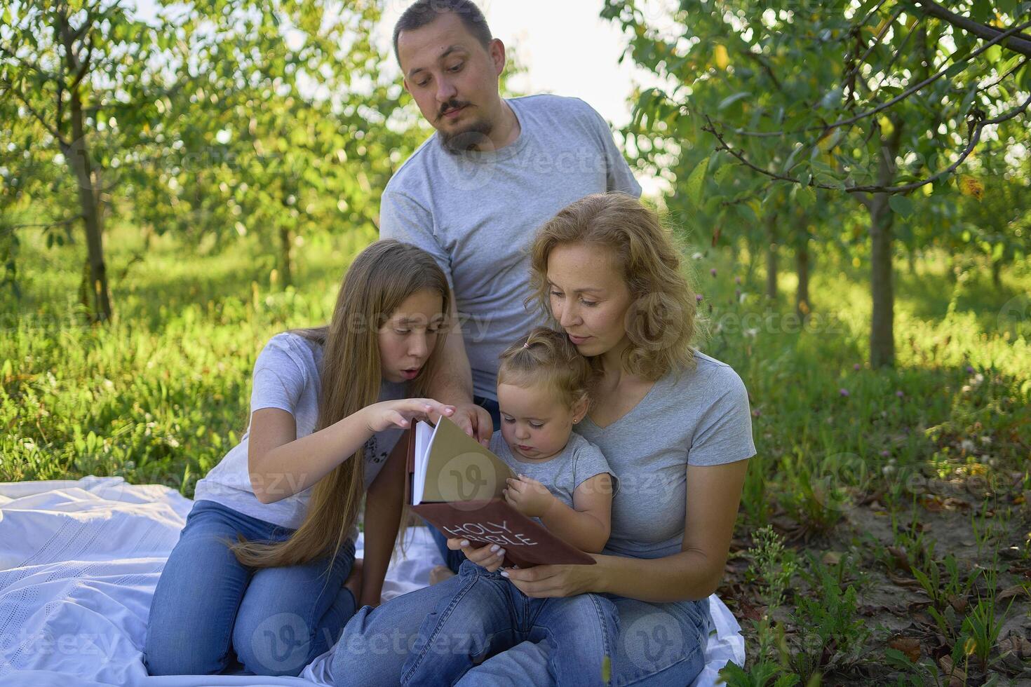 family reading the holy bible on a picnic in the garden photo