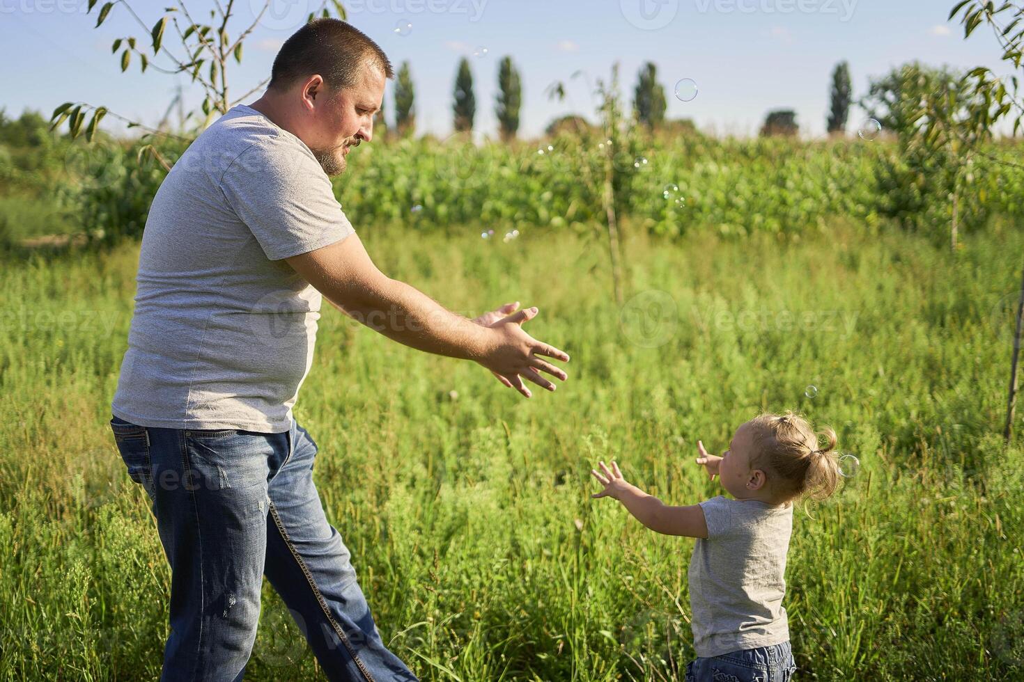 a family of four is playing catch bubbles in the garden photo