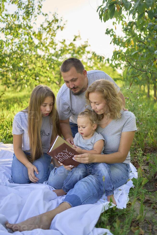 family reading the holy bible on a picnic in the garden photo
