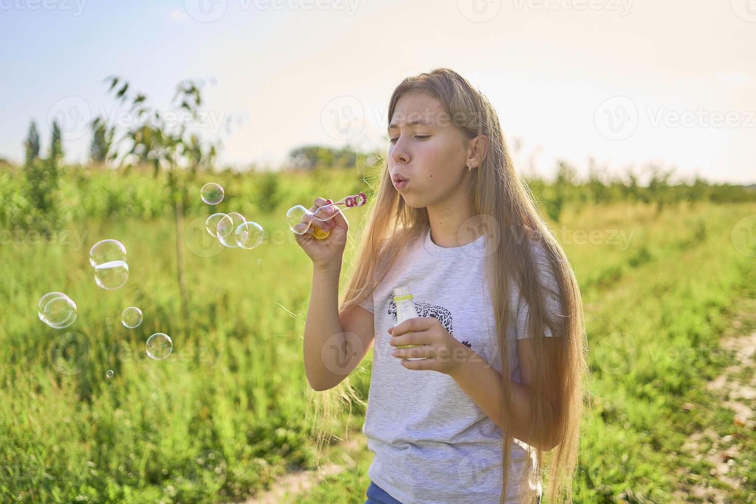 teen sister blowing soap bubbles for toddler photo