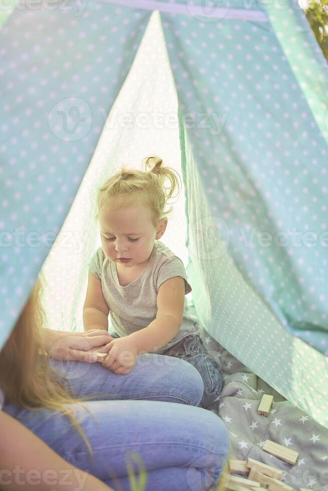 family with toddler playing in wigwam in garden photo