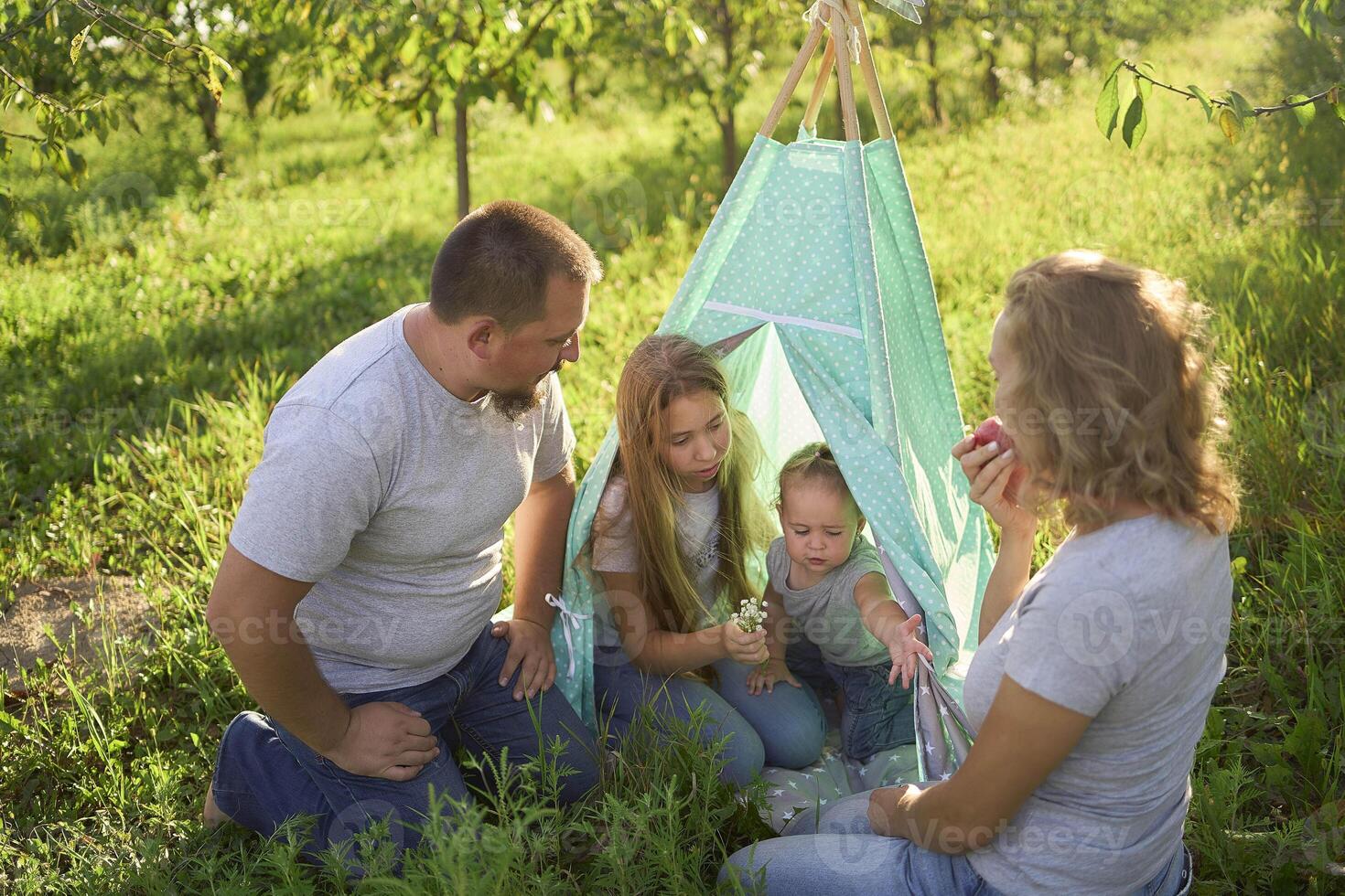 family with toddler playing in wigwam in garden photo