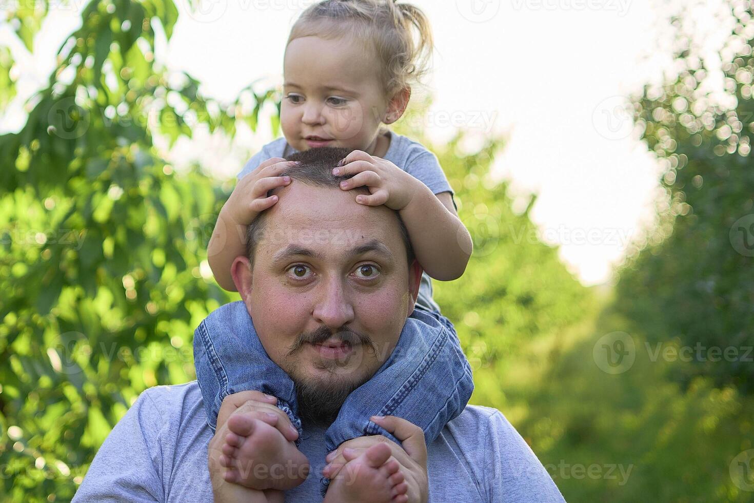 a father plays with a toddler on his shoulders photo