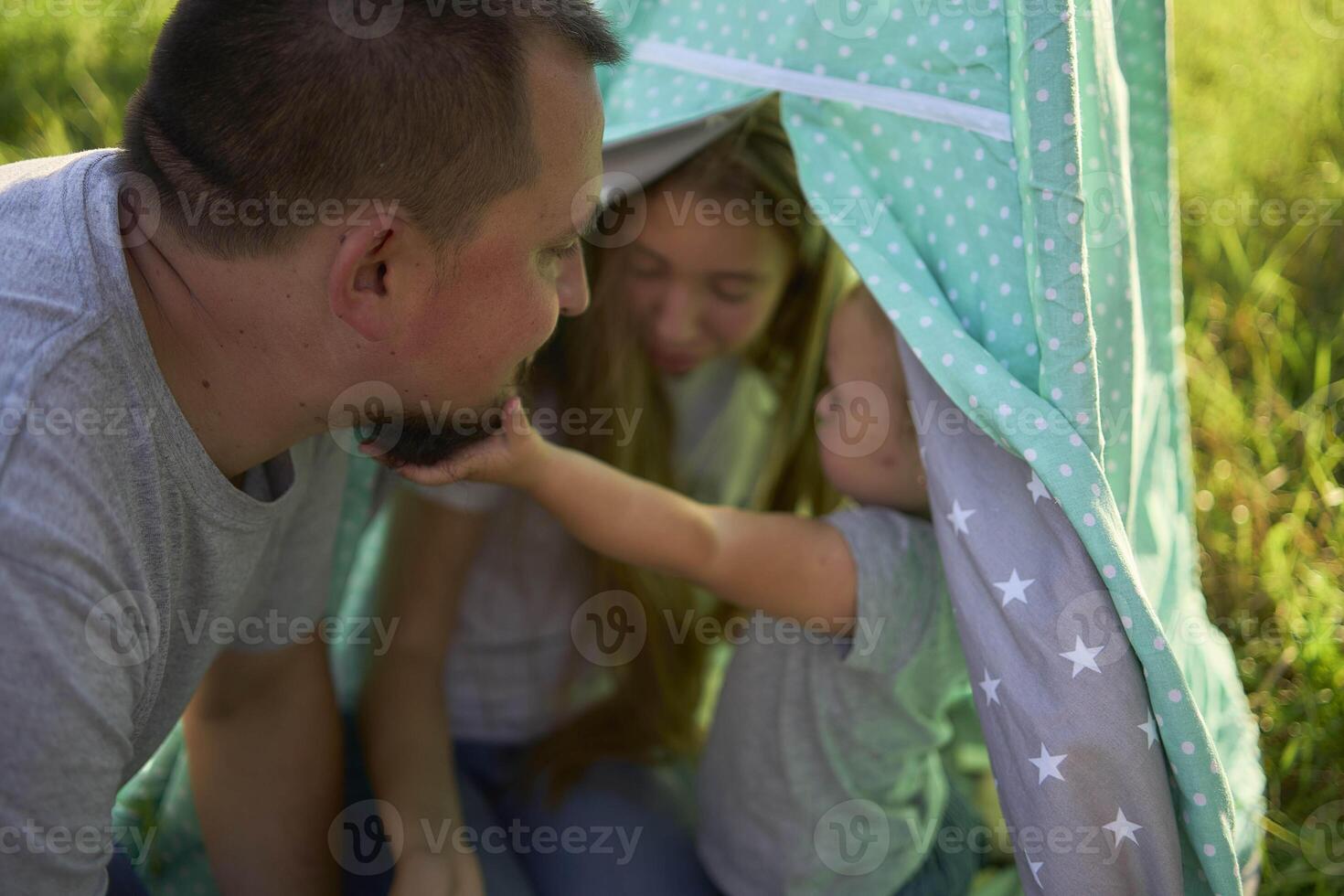 family with toddler playing in wigwam in garden photo