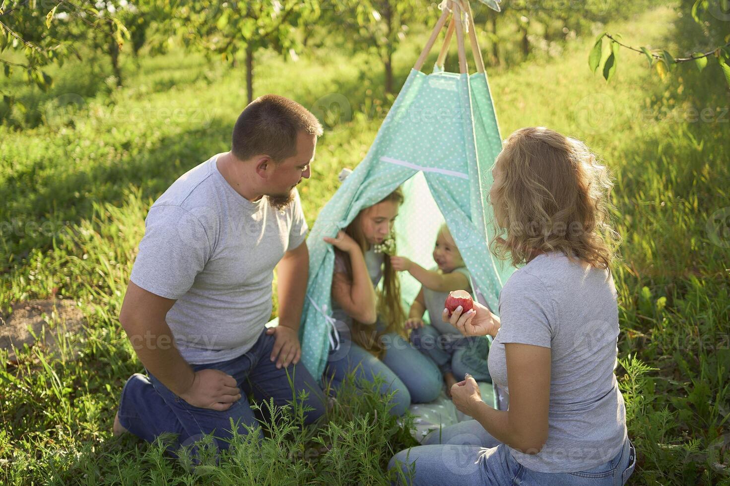 family with toddler playing in wigwam in garden photo