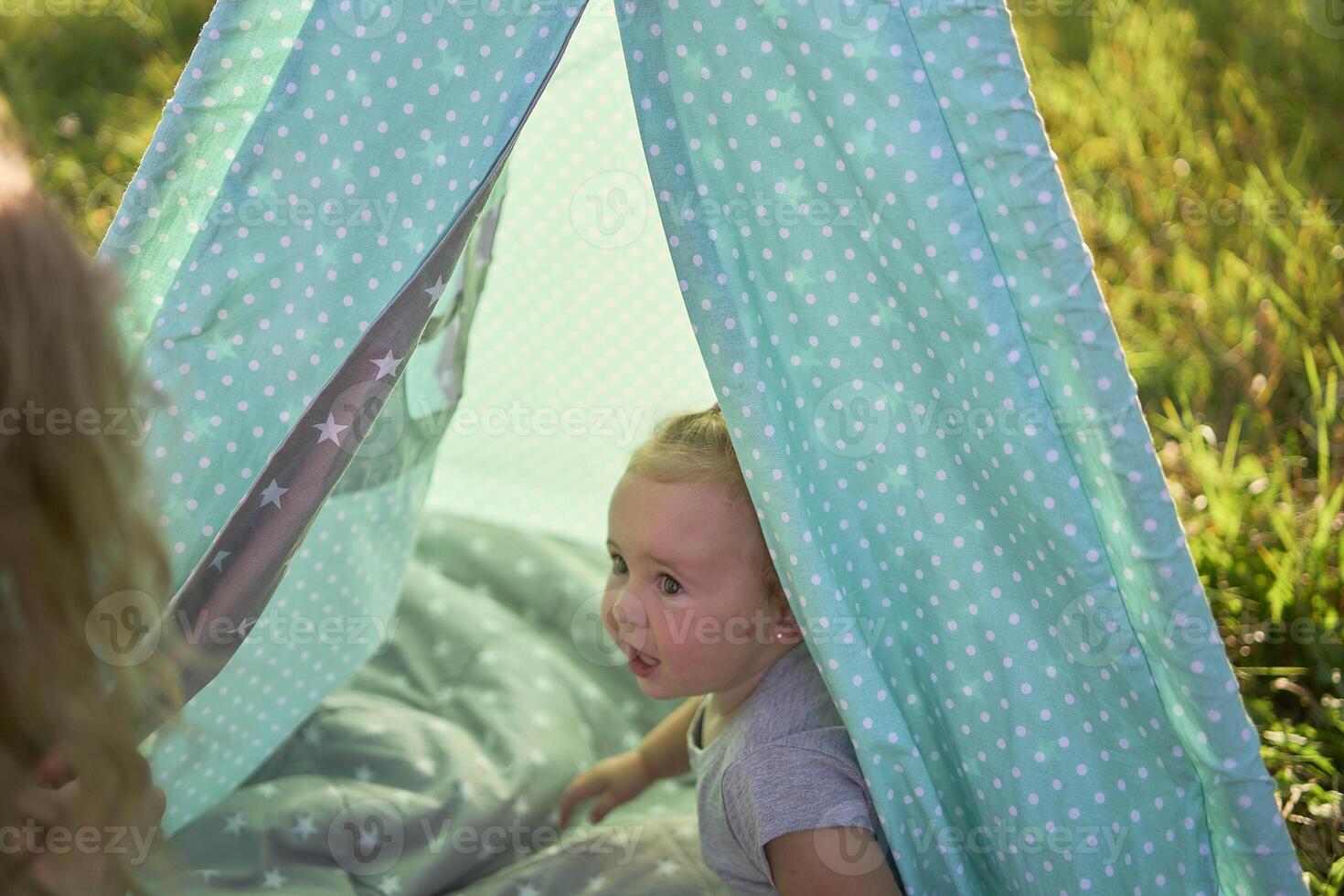 family with toddler playing in wigwam in garden photo