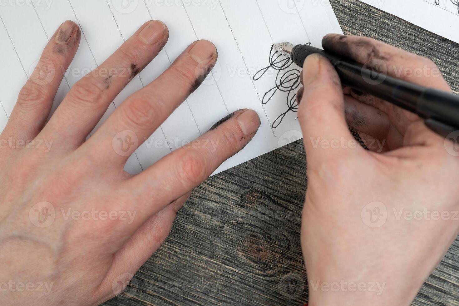 Calligraphy training. Fountain pen in ink-stained hands. photo
