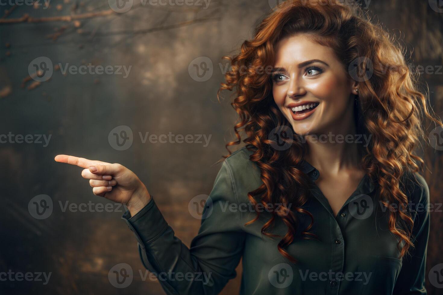 A beautiful red-haired, freckled, curly smiling girl on a green background shows with her hand. photo