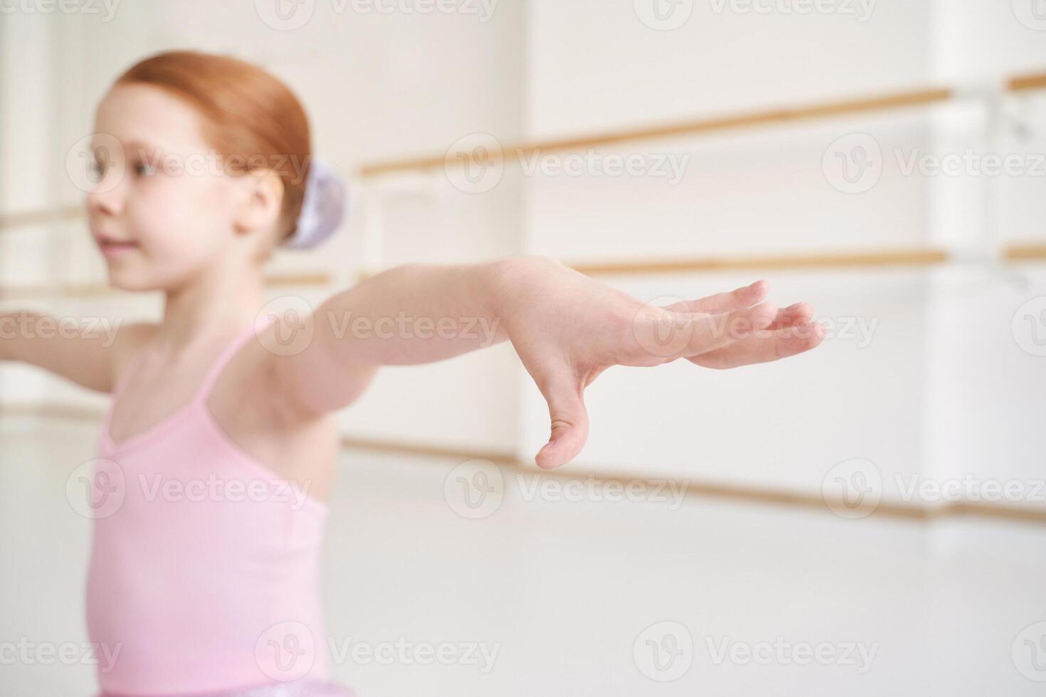 Young ballet girl at studio lesson. Training performance. Stretching exercise pose. Ballerina practice balance technique. Classical elegance fitness. Dancing costume. Close up. Pink dress, skirt photo