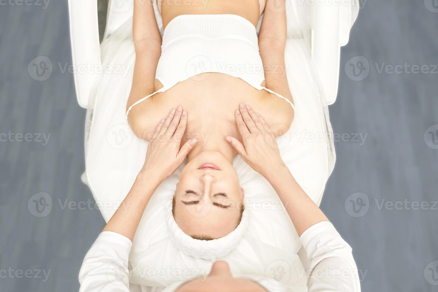 Face massage at luxury spa salon. Doctor hands. Pretty female patient. Beauty treatment. Healthy skin procedure. Young woman head. Light background. Facial rejuvenation dermatology mask. Detox therapy photo