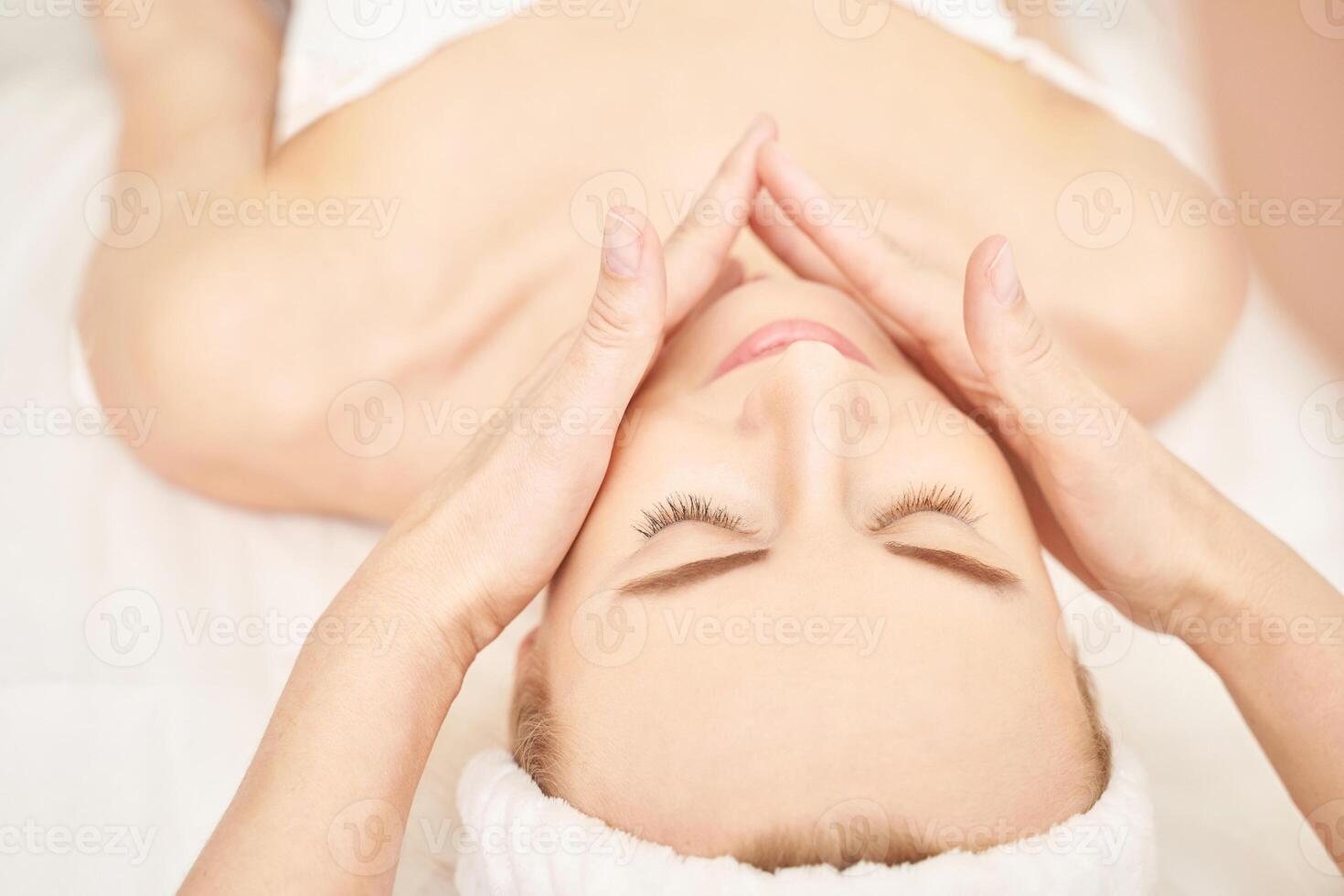 Face massage at luxury spa salon. Doctor hands. Pretty female patient. Beauty treatment. Healthy skin procedure. Young woman head. Light background. Facial rejuvenation dermatology mask. Detox therapy photo