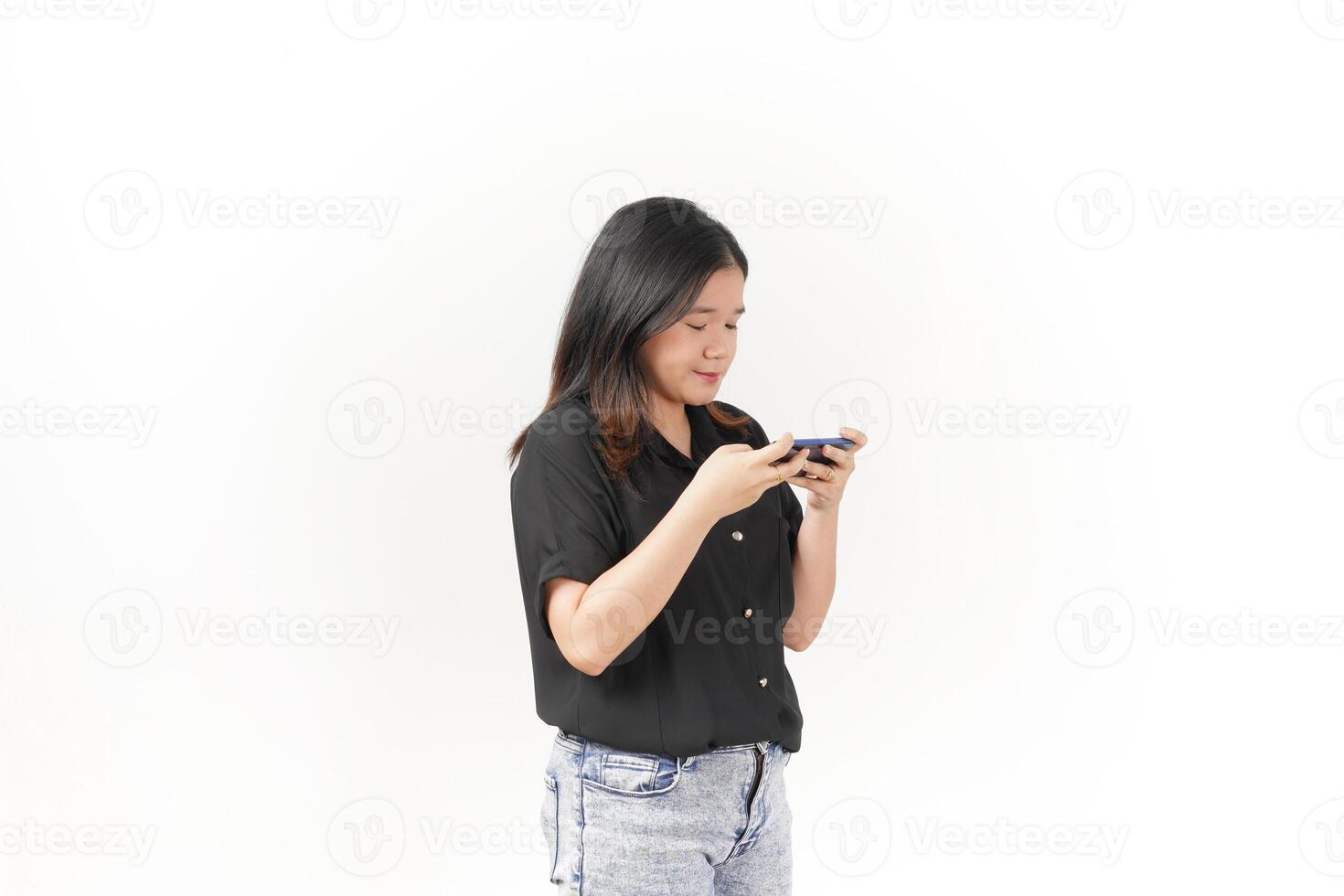 Young Asian woman playing game on smartphone wearing Black t-shirt and jeans isolated on white background photo