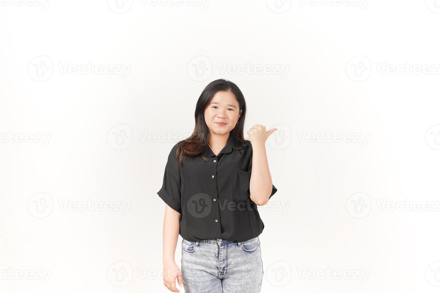 Young Asian woman pointing aside wall copy space wearing Black t-shirt and jeans isolated on white background photo