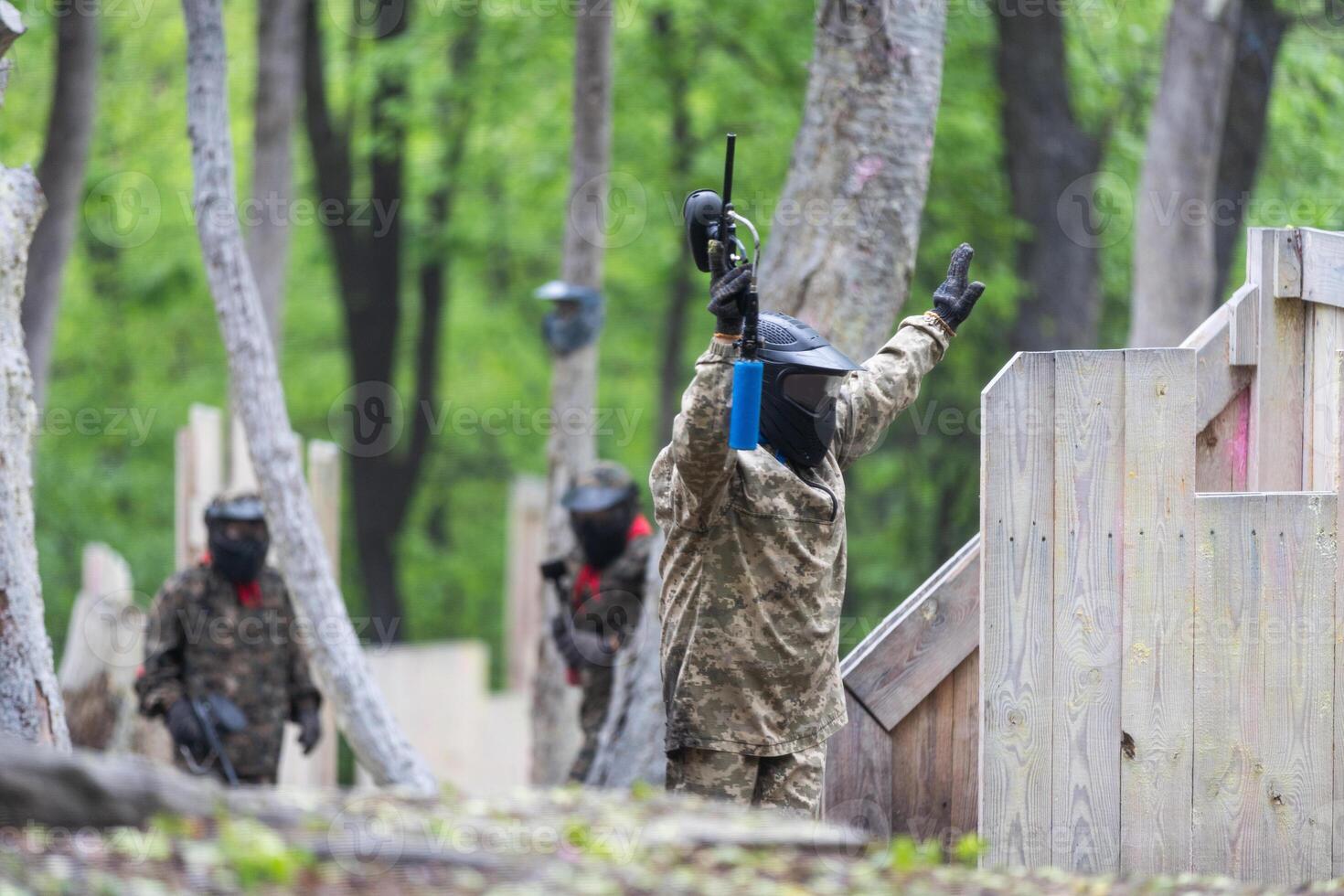 Warriors in camouflage and masks playing paintball photo