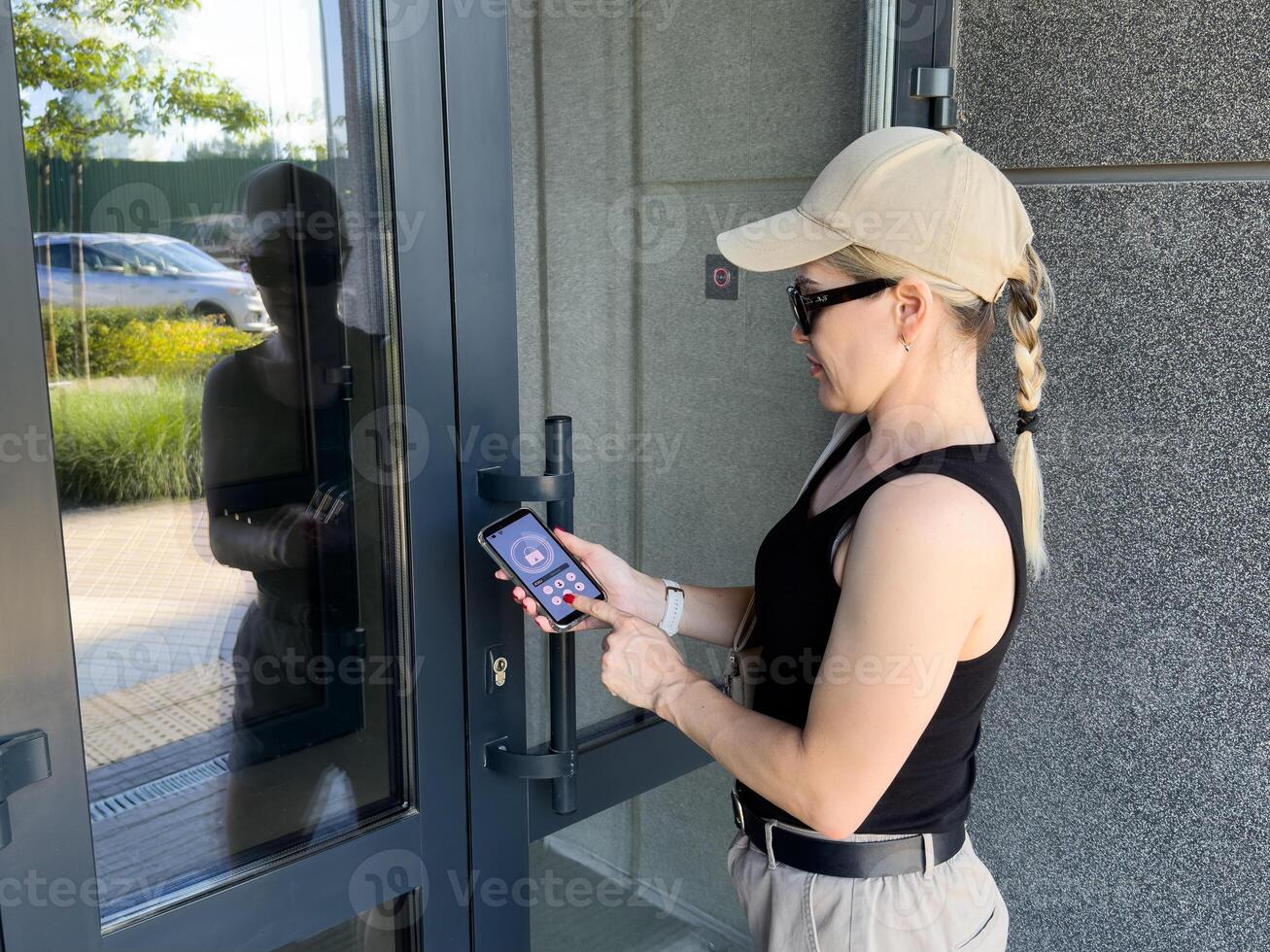 Close up of woman using intercom at building entrance. photo