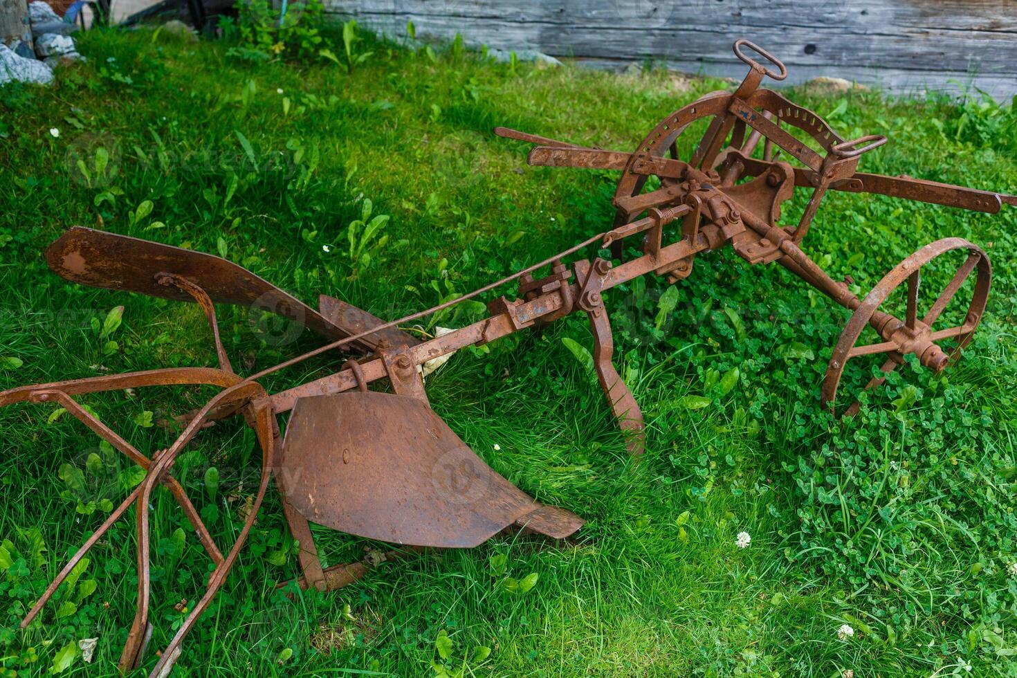 old rusty plow lying on the grass photo