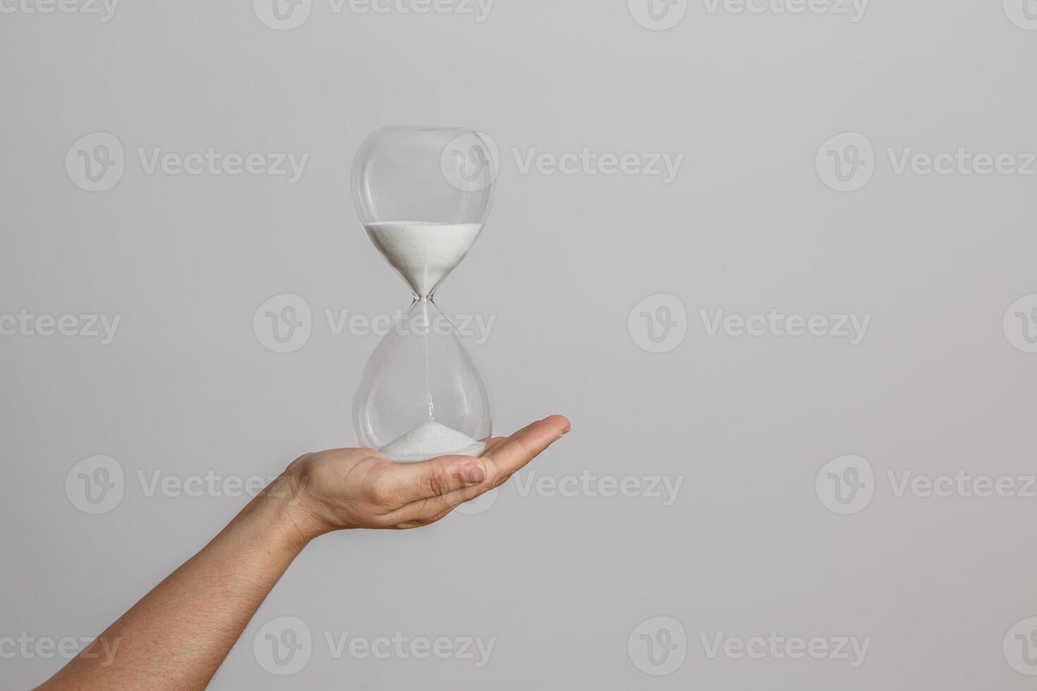 Hand Holding Sand Timer Against Neutral Background Signifying Time Management Importance photo