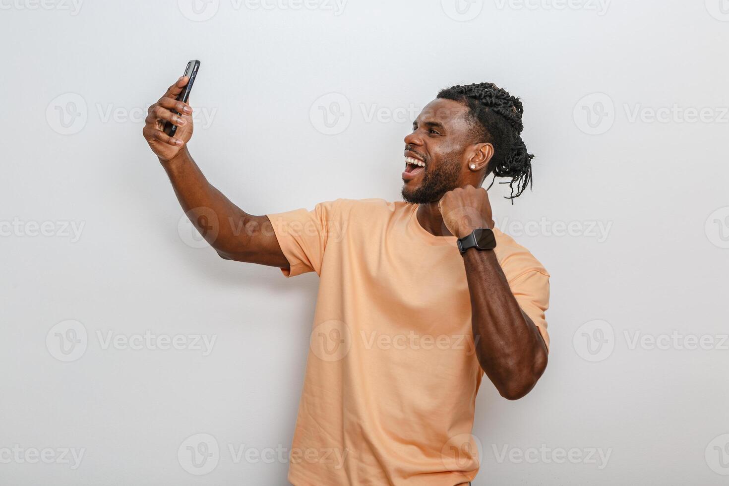 Man taking a selfie smiling and celebrating on a well-lit white background photo