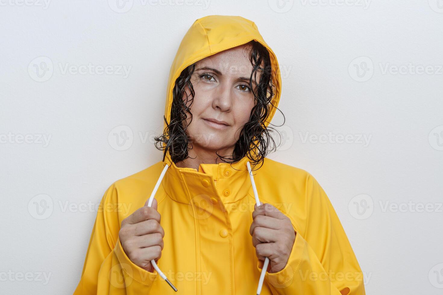 Woman in yellow raincoat smiling with wet hair on a white background photo