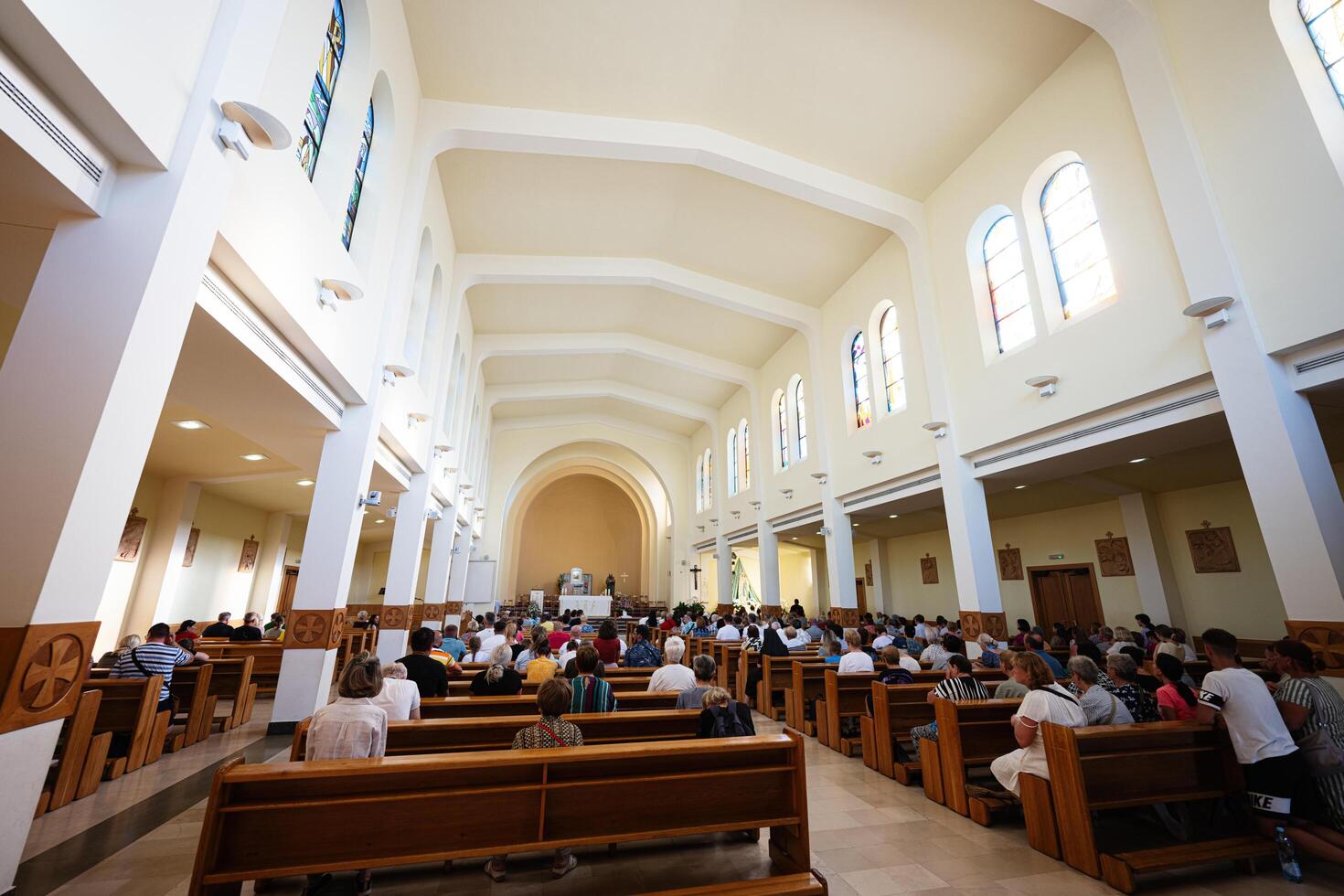 Medjugorje, Bosnia and Herzegovina - 15 July 2024 Interior view of a church congregation during a service with natural light streaming through stained glass windows photo