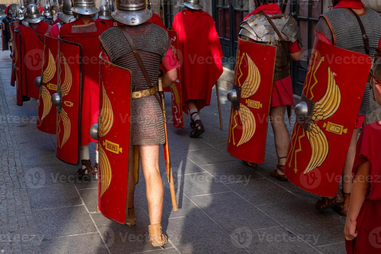 Roman legionaries with metal armor and shield at a historical reenactment event seen from the back. photo