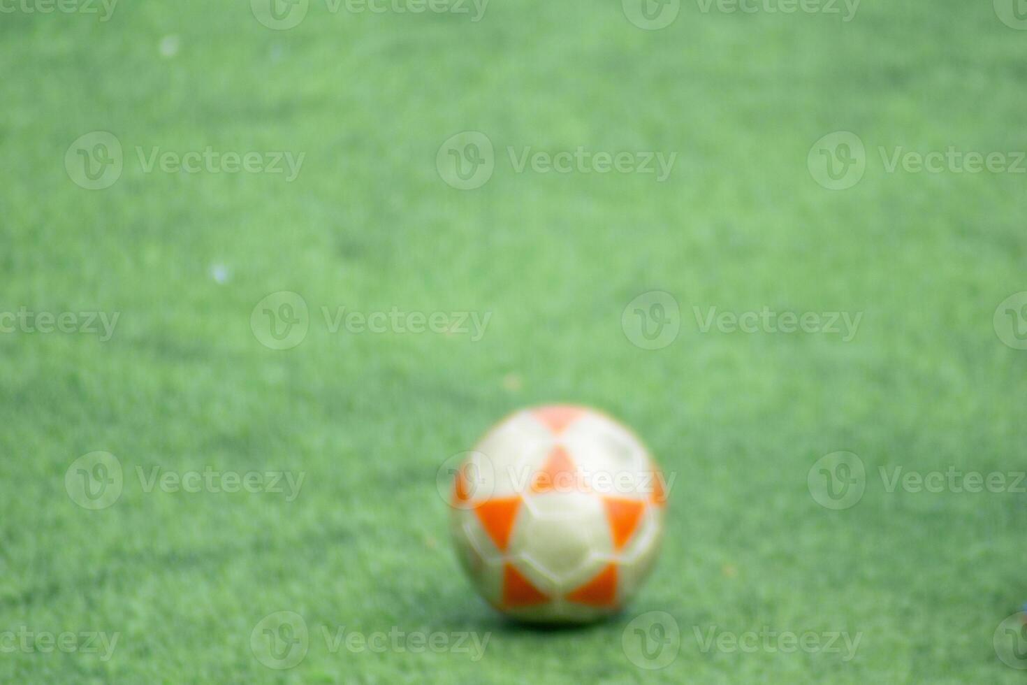 photograph of out-of-focus image of a football ball on an artificial turf soccer field photo