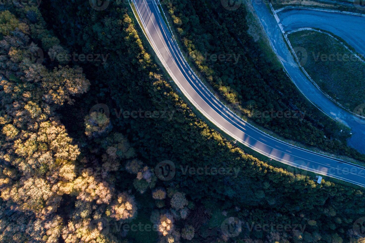 overhead drone aerial view of a mountain road at sunset photo