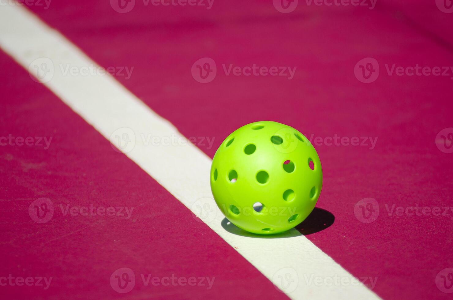 green pickleball ball isolated on a pink court photo
