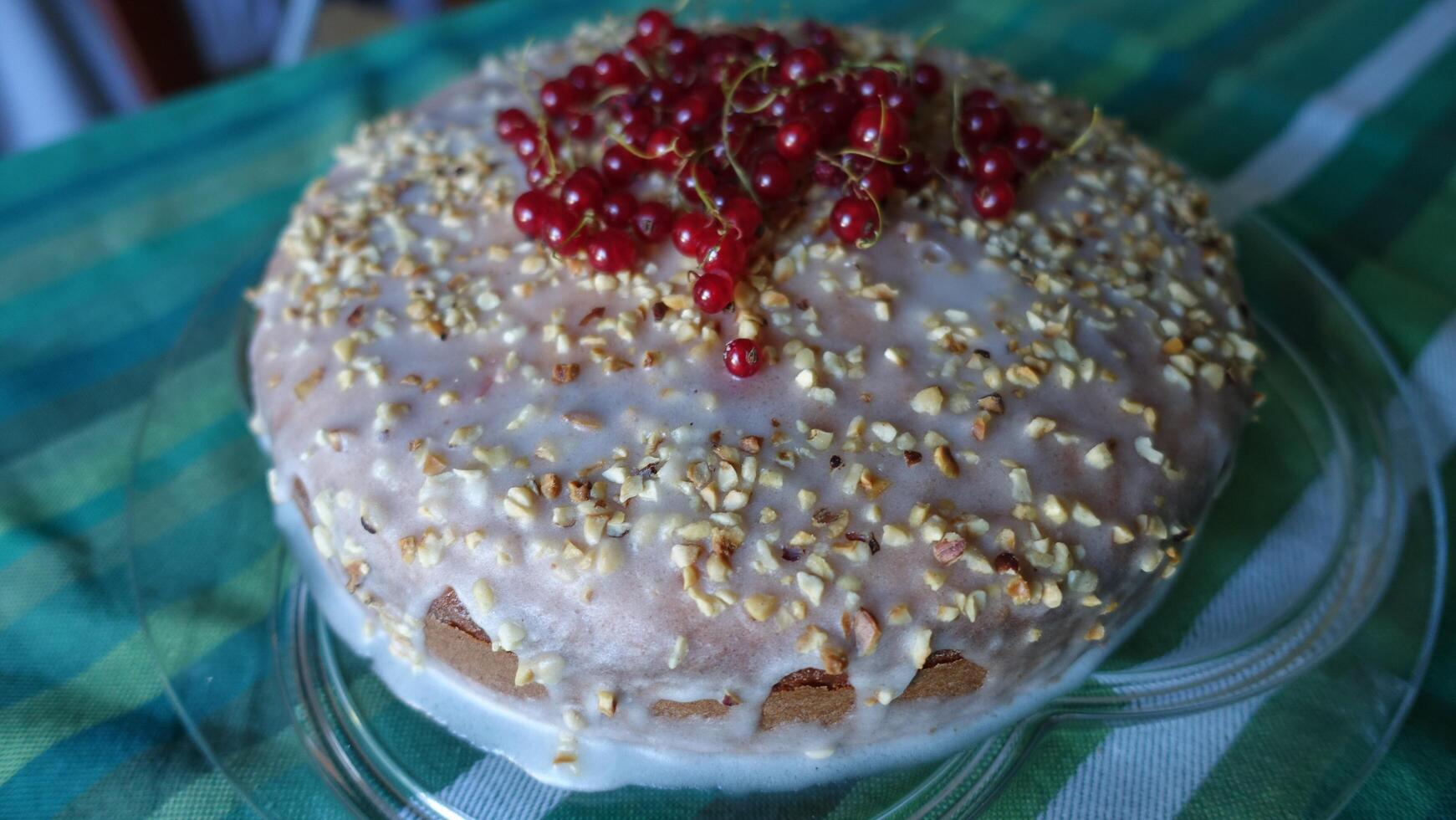 cake with sugar glaze, chopped hazelnuts and red currants on top photo