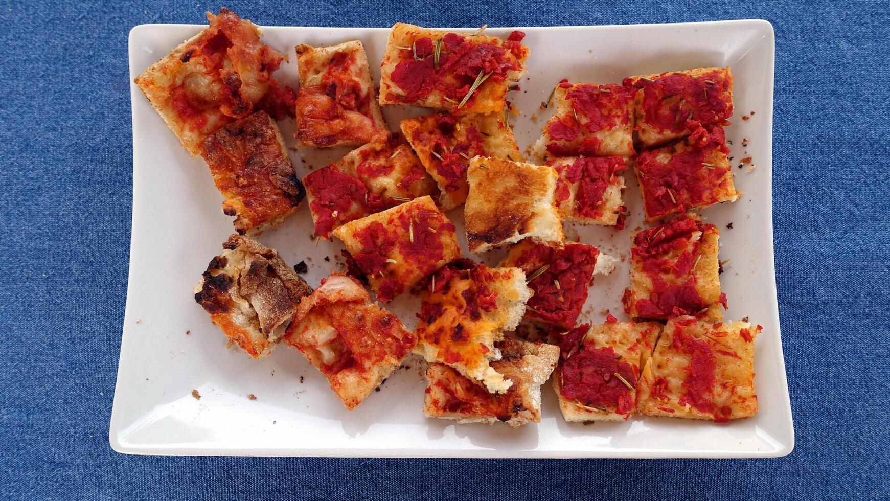 Bites of focaccia with tomato and mozzarella in a rectangular dish. photo